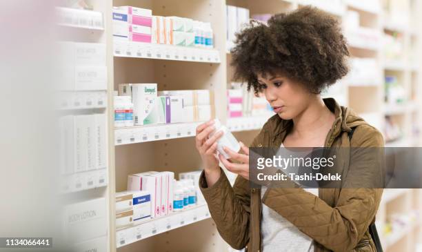 young woman choosing supplement in drugstore - probiotic stock pictures, royalty-free photos & images