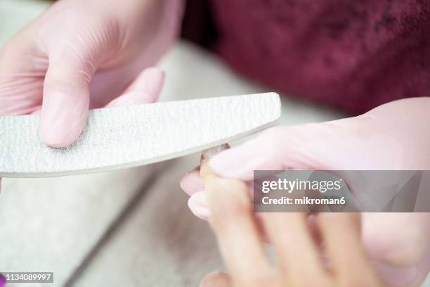 nail technician filling clients nails with a nail file - nail file stock pictures, royalty-free photos & images