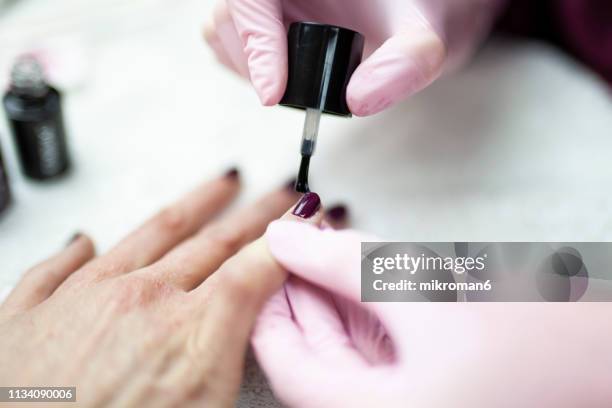 nail technician painting clients nails at a beauty salon - gel nail polish stock pictures, royalty-free photos & images