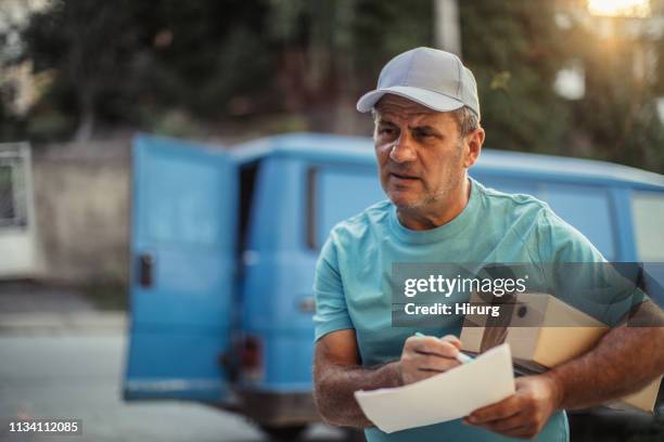 senior delivery man is holding package - home delivery stock pictures, royalty-free photos & images