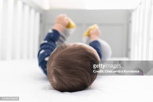 baby laying in the crib in a bright minimalistic room - cot imagens e fotografias de stock