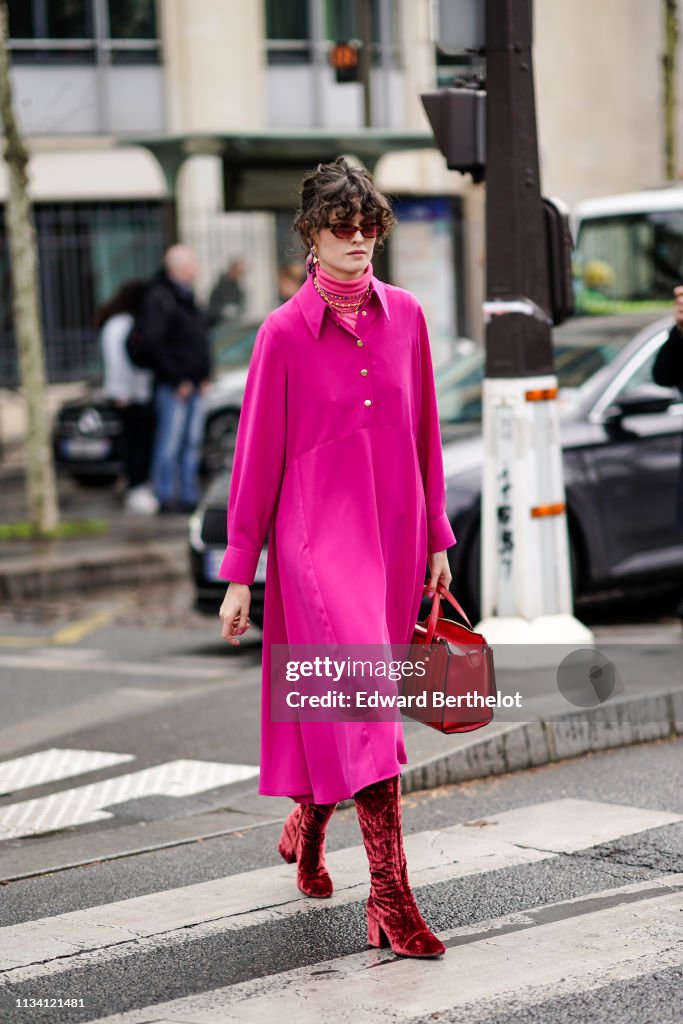 A guest wears a pink coat, turtleneck top, a red bag, red boots ...