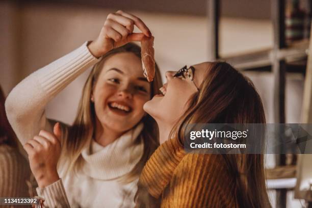 vrouw proeverij heerlijke ham - sisters feeding stockfoto's en -beelden