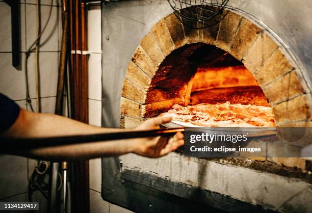 man putting pizza in oven - making pizza stock pictures, royalty-free photos & images