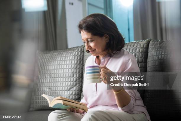 porträt der seniorin sitzt auf sofa zu hause - tee indien trinken stock-fotos und bilder