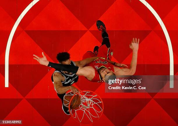 Derrick White of the San Antonio Spurs dunks against Alex Len of the Atlanta Hawks in the first half at State Farm Arena on March 06, 2019 in...