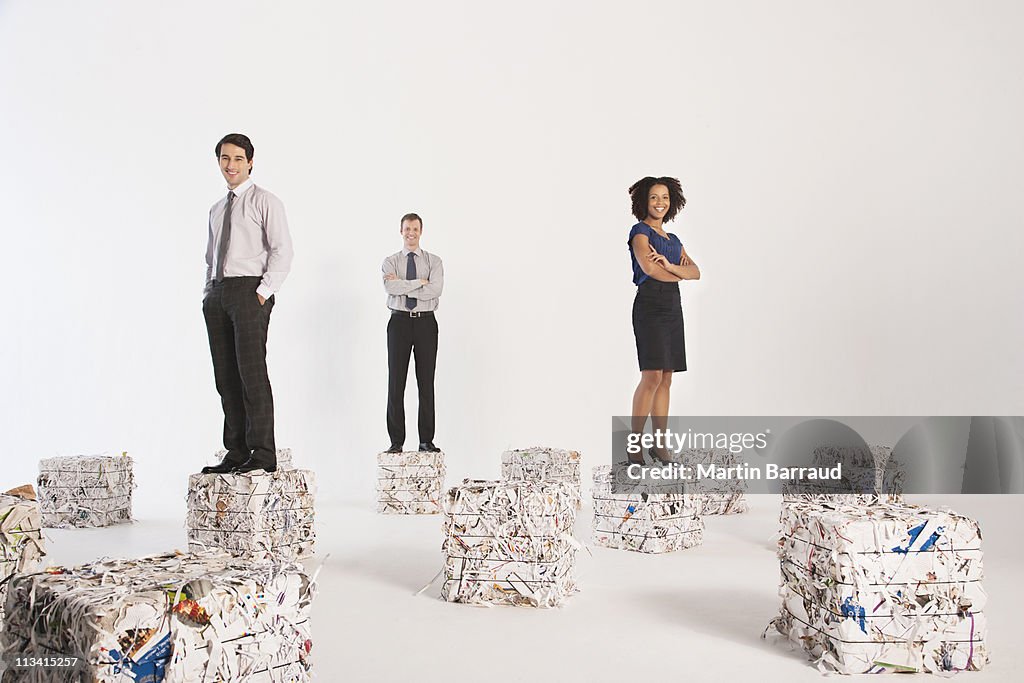 Businesspeople standing on bales of paper