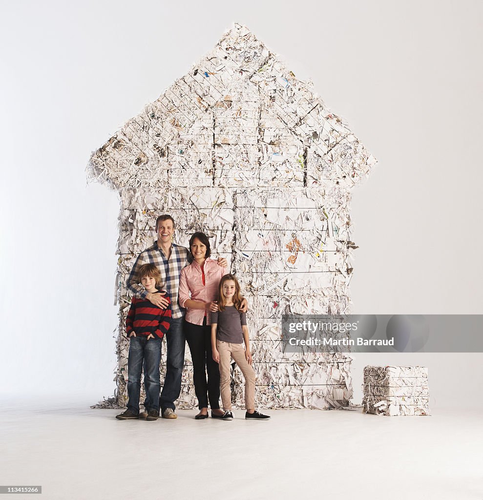 Family standing by 'house' made of paper bales