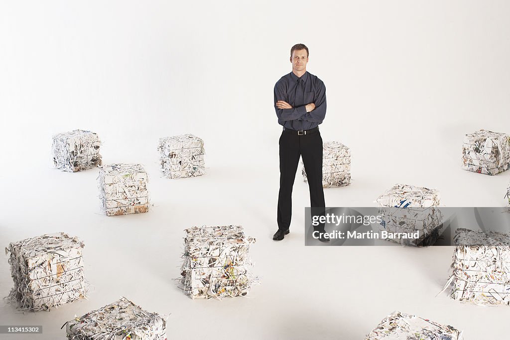 Businessman standing with bales of paper