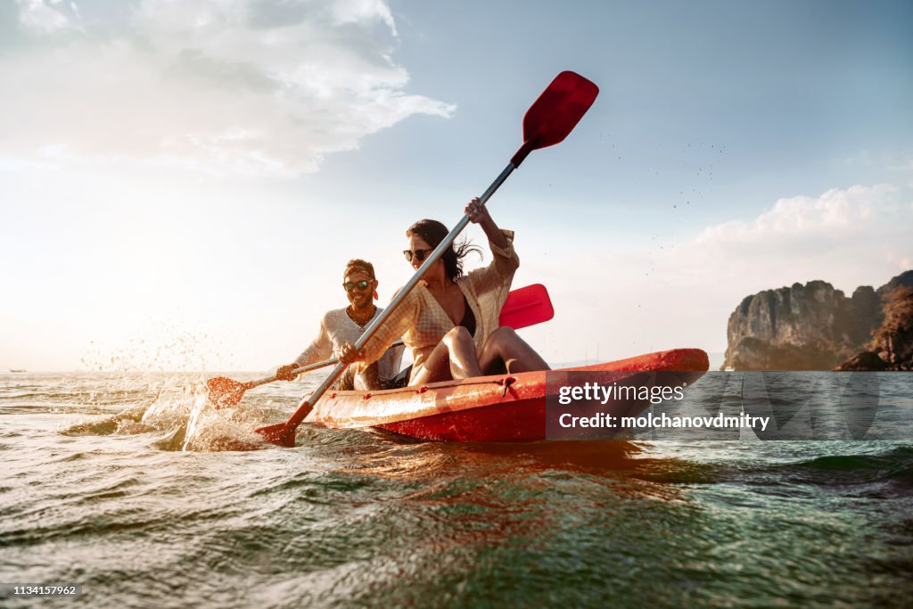 Promenades de couples heureux par le kayak de mer ou le canoë