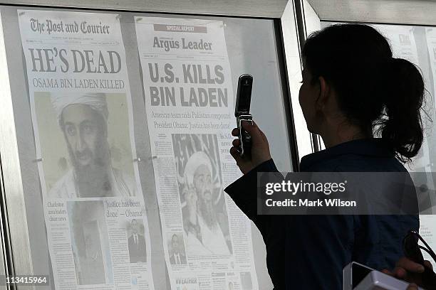 Passerby takes pictures of newspaper headlines reporting the death of Osama Bin Laden, in front of the Newseum, on May 2, 2011 in Washington, DC....