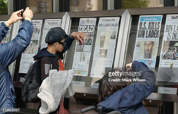 Passers by take pictures of newspaper headlines reporting the death of Osama Bin Laden, in front of the Newseum, on May 2, 2011 in Washington, DC....