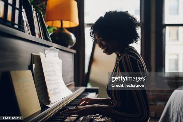 retrato clave bajo de una mujer tocando el piano en su apartamento de los ángeles - clave baja fotografías e imágenes de stock