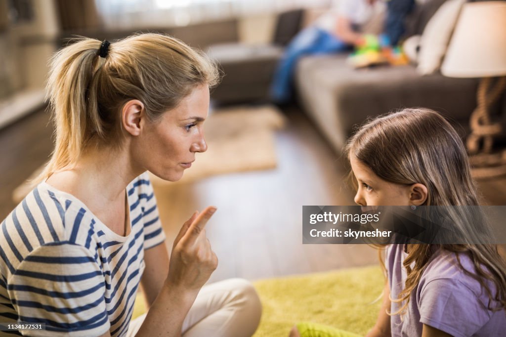 Young mother scolding little daughter in the living room.