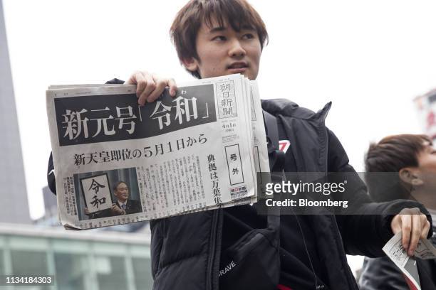 Man distributes copies of an extra edition of the Asahi Shimbun newspaper reporting on the announcement of the name of Japan's next imperial era...