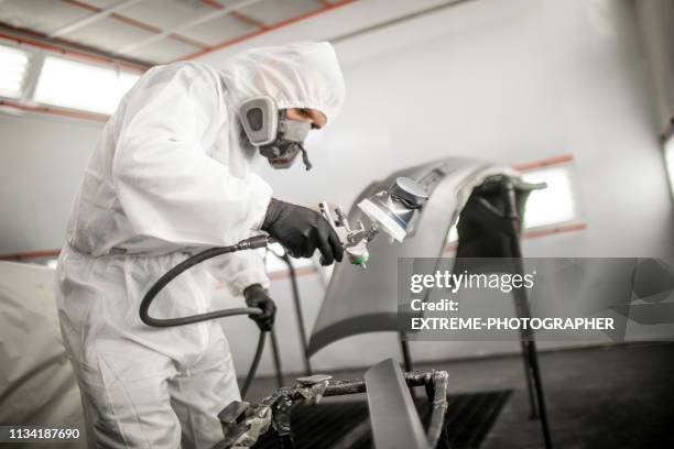 professional car painter blasting a car part with a base coat paint in a workshop - spray booth stock pictures, royalty-free photos & images