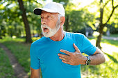 Senior man with chest pain suffering from heart attack during jogging