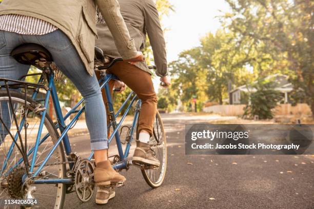 couple riding bicycles on suburban street - tandem stockfoto's en -beelden