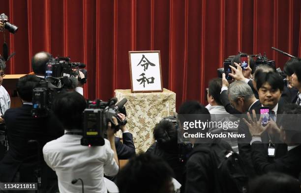 Media members gather in front of a piece of calligraphy showing the name of Japan's new era, "Reiwa," at the prime minister's office in Tokyo on...