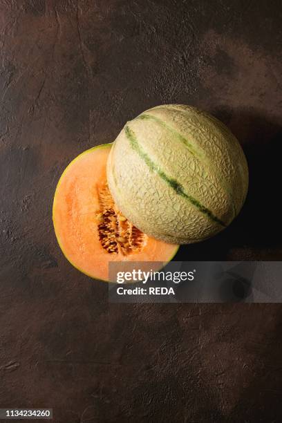 Half of ripe organic Cantaloupe melon with seeds over dark brown texture background. Flat lay. Space.