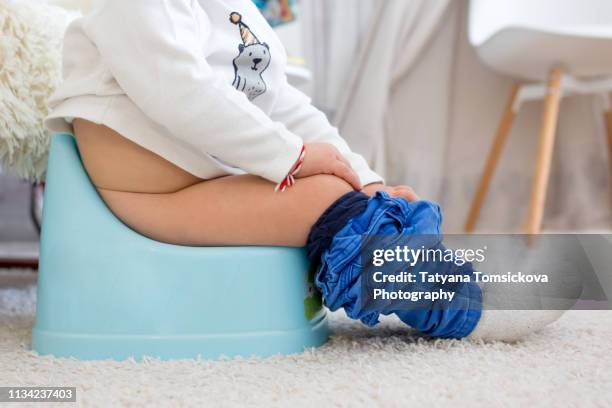children's legs in boots, hanging down from a chamber-pot on a home interior - kids peeing - fotografias e filmes do acervo
