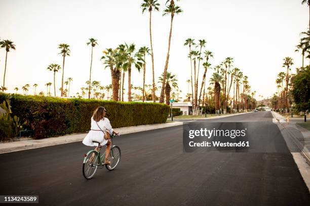 usa, california, palm springs, woman riding bicycle on the street - palm springs california stock-fotos und bilder