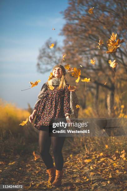 happy pregnant woman standing on forest path playing with autumn leaves - single leaf stock-fotos und bilder