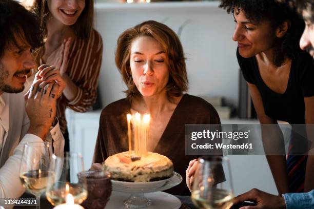 friends celbrating birthday of a young woman, blowing out birthday candles - birthday candle fotografías e imágenes de stock