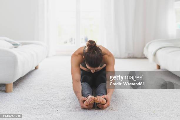 woman sitting on the floor practicing yoga - woman bending over imagens e fotografias de stock