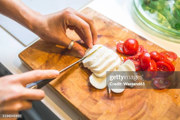 woman preparing caprese salad on chopping board - mozzarella stock-fotos und bilder