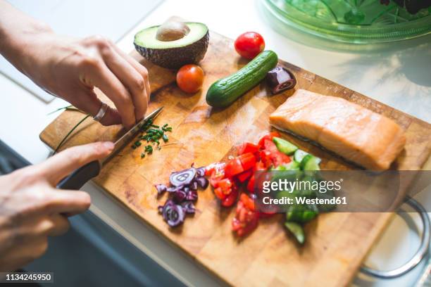 woman preparing vegetables and salmon on chopping board - chopped tomatoes foto e immagini stock