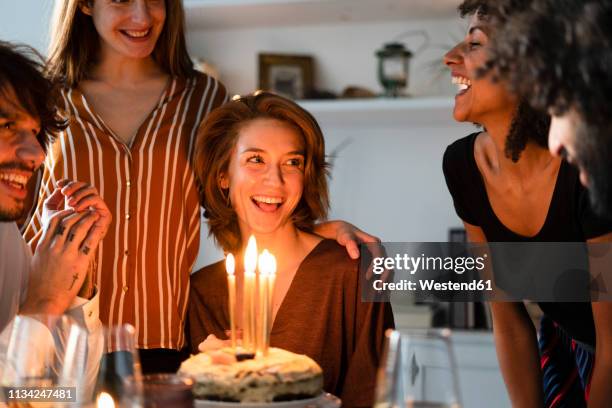 friends surprising young woman with a birthday cake with burning candles - surprise birthday party stock pictures, royalty-free photos & images