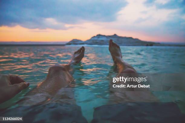 guy floating in the dead sea during vacations with sunset light. - dead sea foto e immagini stock