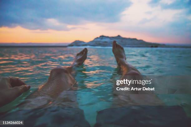 guy floating in the dead sea during vacations with sunset light. - dead sea float stock pictures, royalty-free photos & images