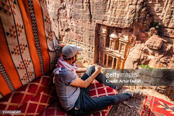 guy in the perfect place to contemplate the al-khazneh treasury tomb in the city of petra from above. - the cemetery for foreigners bildbanksfoton och bilder