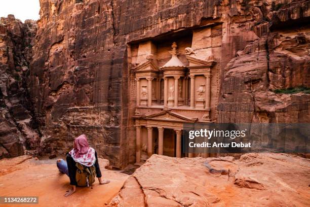 tourist contemplating the al-khazneh treasury tomb in the city of petra from viewpoint. - pétra photos et images de collection