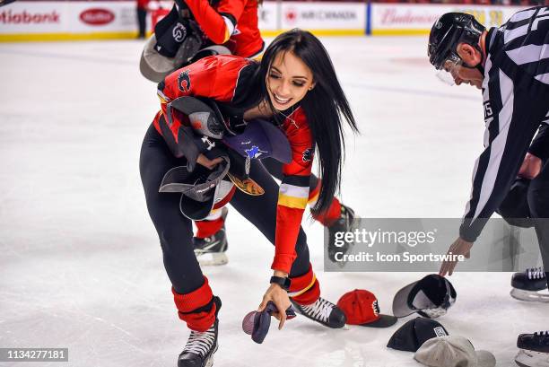 Calgary Flames ice girl picks up hats after Calgary Flames Center Sean Monahan scores a goal during the third period of an NHL game where the Calgary...