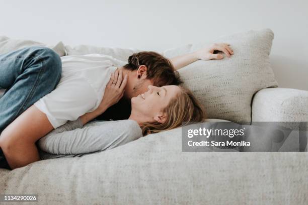 couple hugging on sofa - couple kissing stock-fotos und bilder