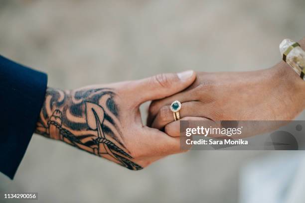 bride and tattooed groom holding hands, cropped - couple jewelry stockfoto's en -beelden