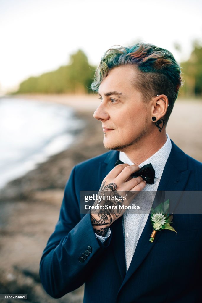 Bridegroom with hand tattoo looking out from lakeside