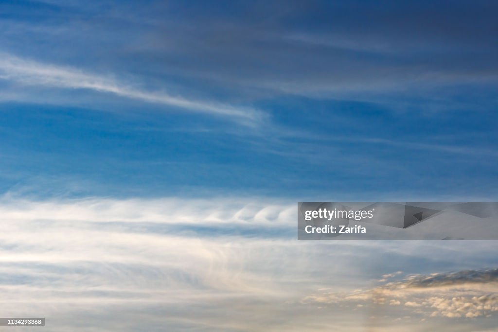 Kelvin, Helmholtz instability clouds wavy on blue sky, feathery curls