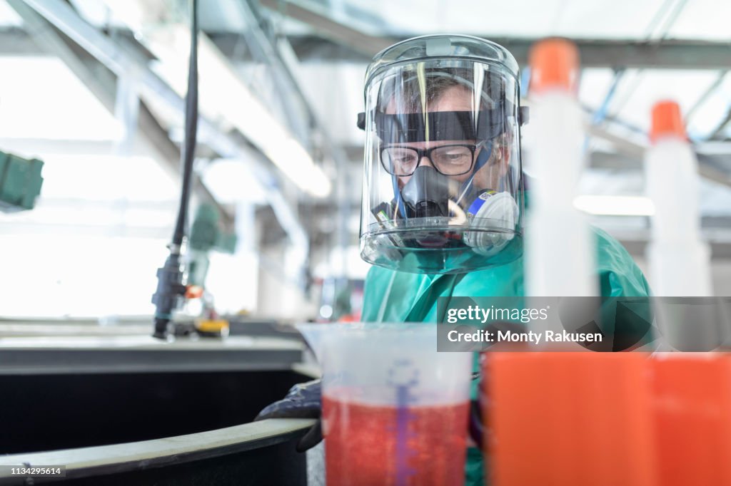 Worker pouring chemical into mixing tanks in chemical factory