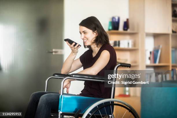 woman in wheelchair using cellphone - sigrid gombert stock-fotos und bilder