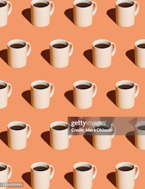 mugs of black coffee in rows against peach background - coffee still life stock pictures, royalty-free photos & images