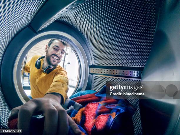 jonge man wassen zijn kleren - launderette stockfoto's en -beelden