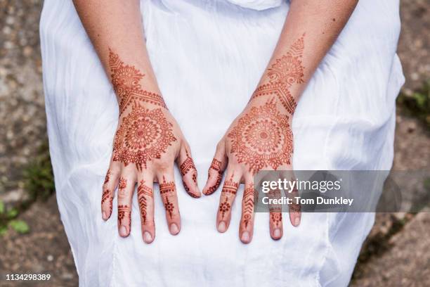 woman in white dress with henna tattoo on hands - mandalas stock-fotos und bilder