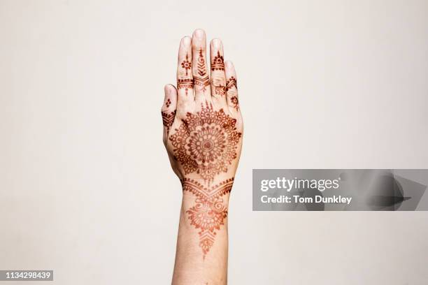 hand with henna tattoo making gesture - henna hands stock-fotos und bilder