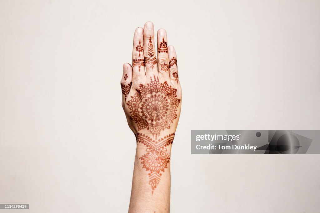 Hand with henna tattoo making gesture