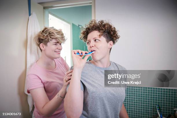 Young homosexual couple in bathroom, brushing teeth