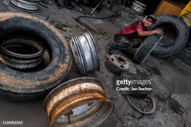 Colombian mechanic works on tires in front of a car repair shop in Barrio Triste on December 7, 2017 in Medellin, Colombia. Barrio Triste is a...